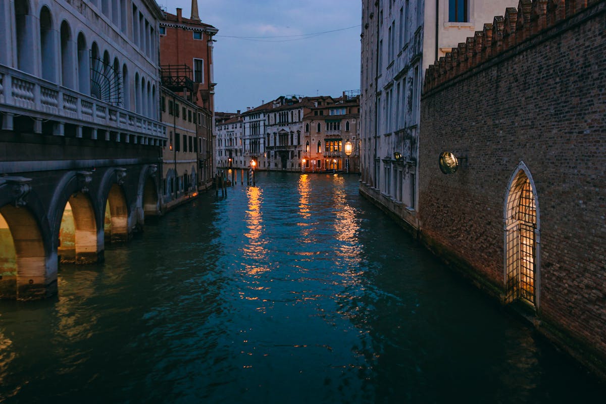 Serene Venice canal at twilight with warm lights reflecting on water