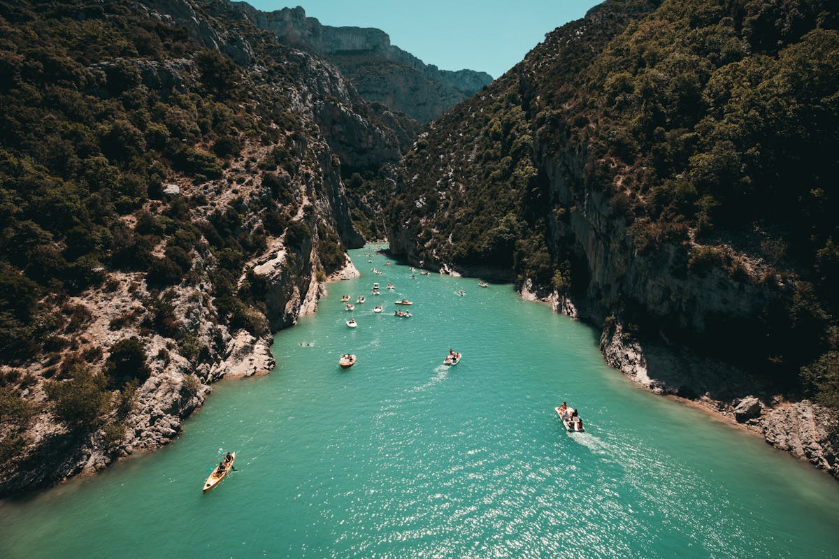 Kayakers paddling through turquoise water surrounded by canyon walls in a river gorge