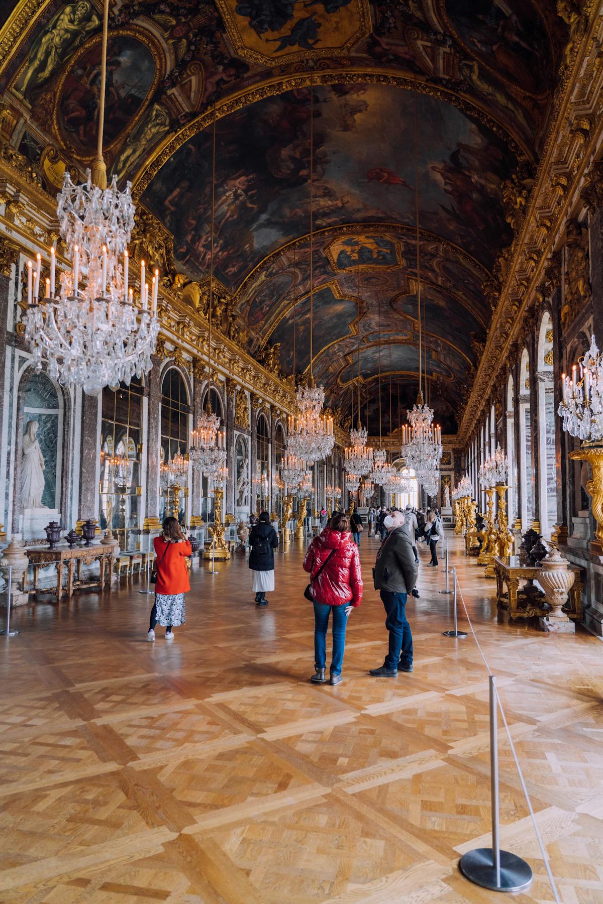The Hall of Mirrors inside the Palace of Versailles with chandeliers and arched windows