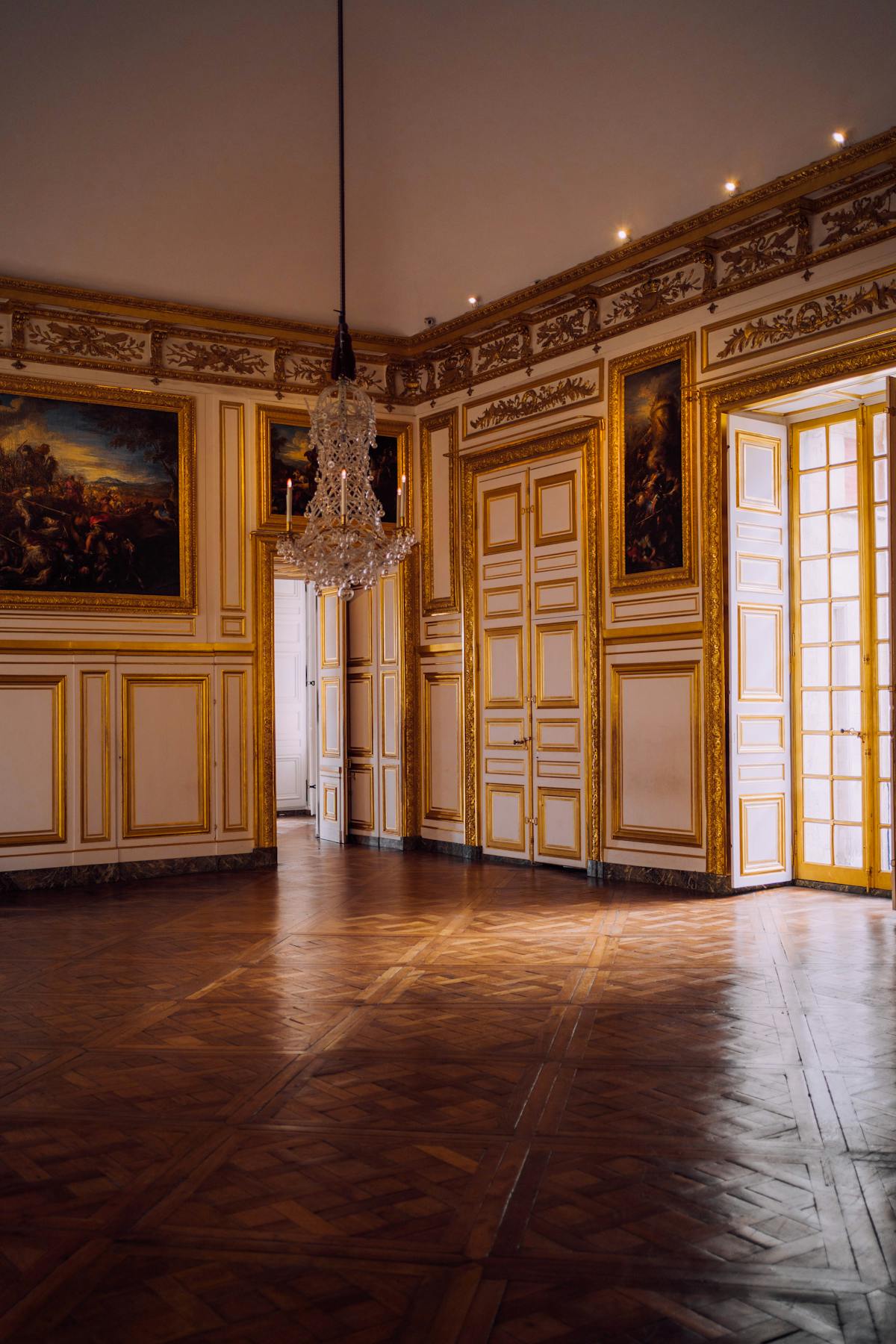 An ornate room inside the Palace of Versailles with a crystal chandelier and decorated walls