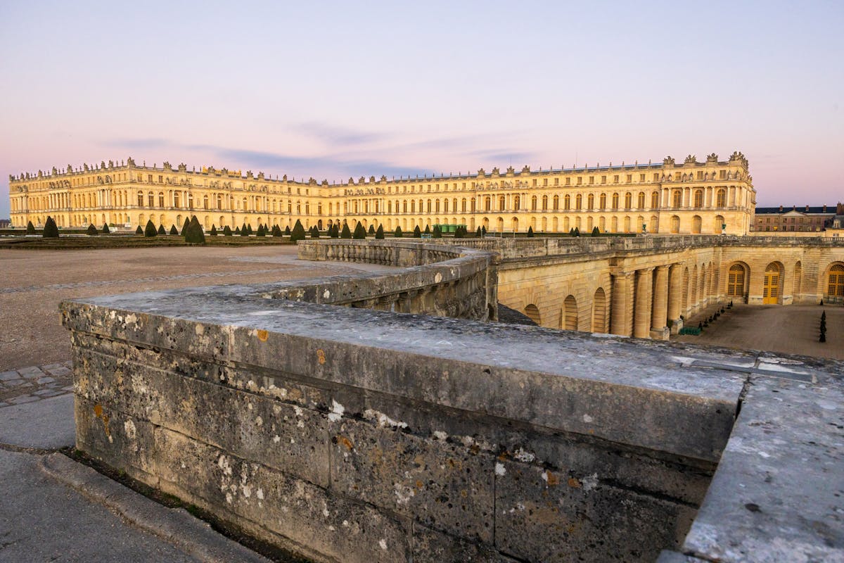 The Palace of Versailles golden facade glowing in late afternoon sunlight
