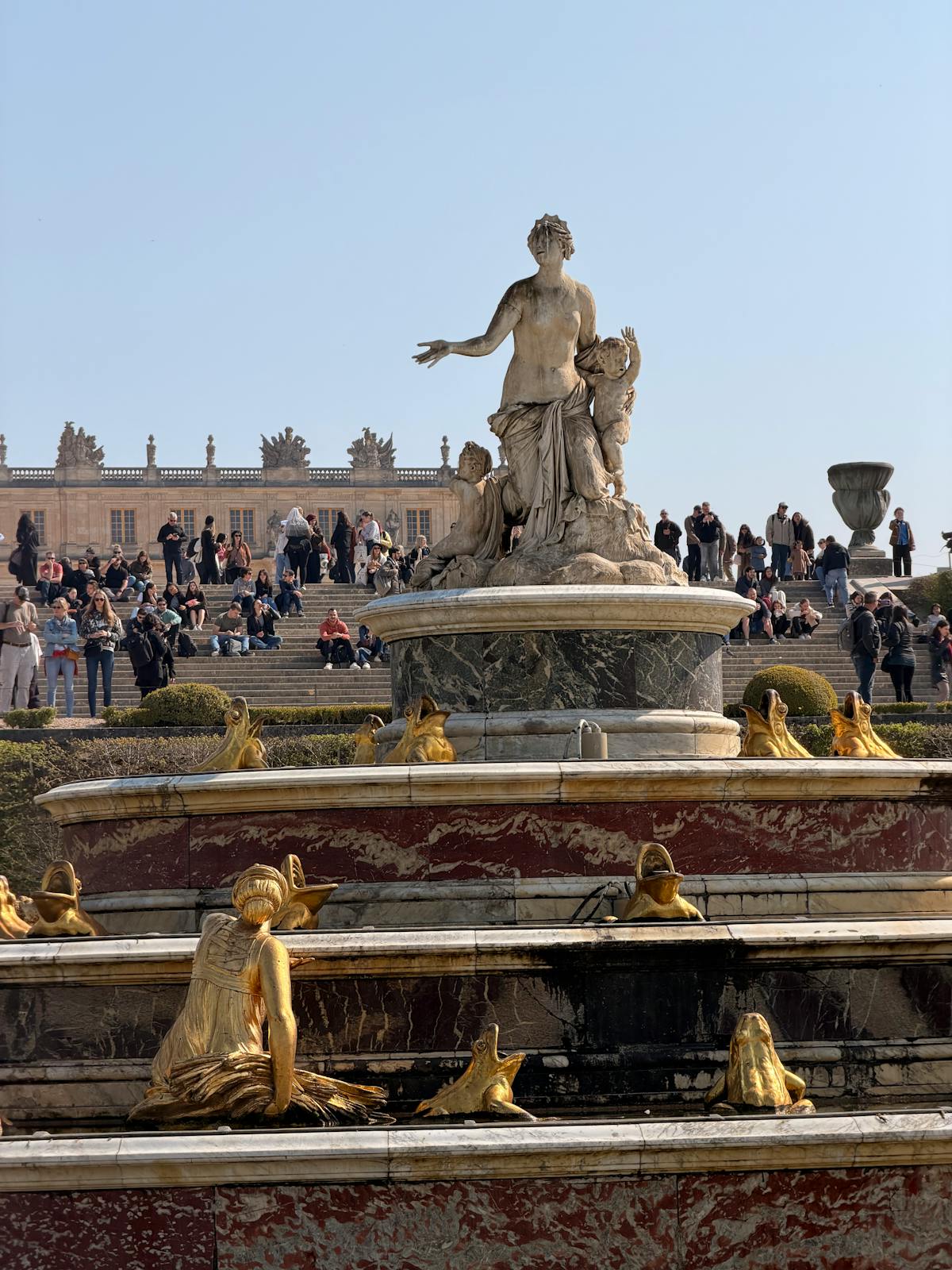 Tourists gathered around the grand fountain at the Palace of Versailles