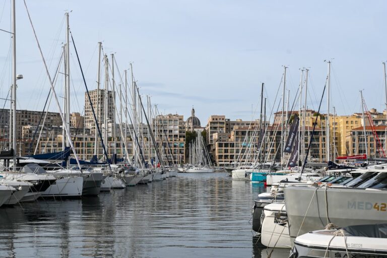 Sailboats docked at Marseille Vieux-Port with the city skyline and Notre-Dame de la Garde in the background