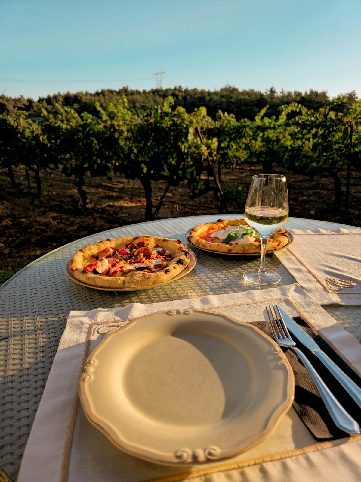Scenic vineyard view with wine glasses and pizza on a table outdoors