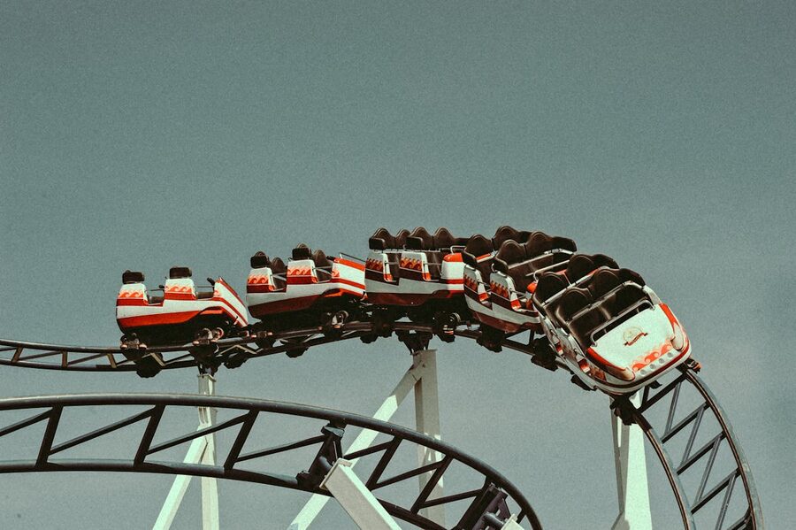 Vintage-style roller coaster cars racing along the track against a clear sky