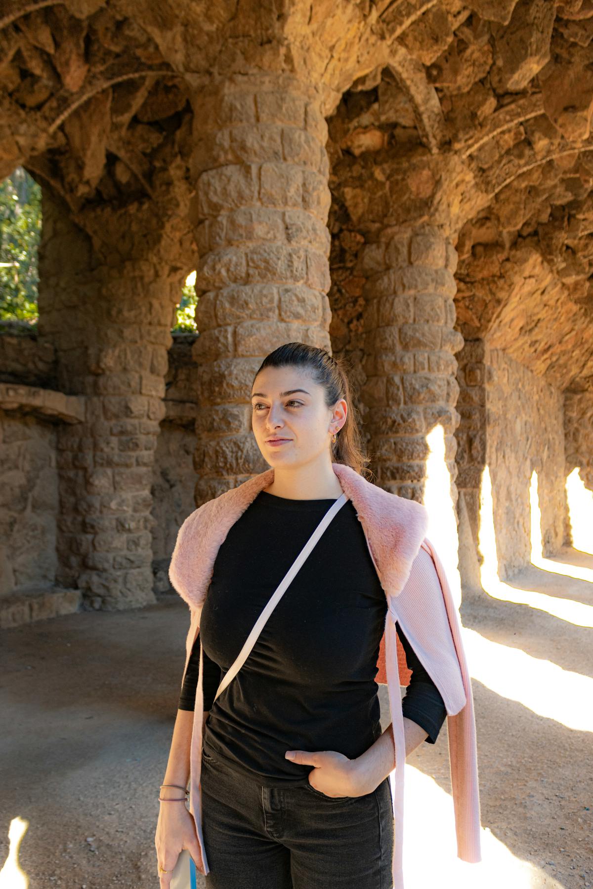 Visitor walking through a sunlit stone archway at Park Guell