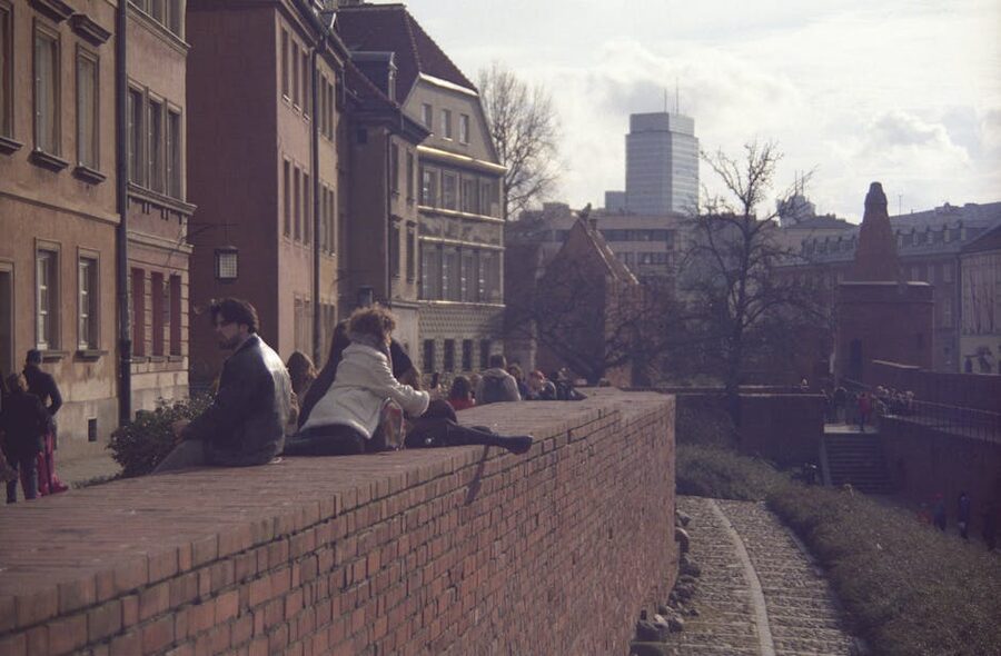People sitting on the historic defensive wall of Warsaw Old Town