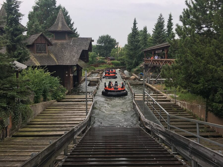 Raft ride flowing through lush greenery and wooden structures at an amusement park