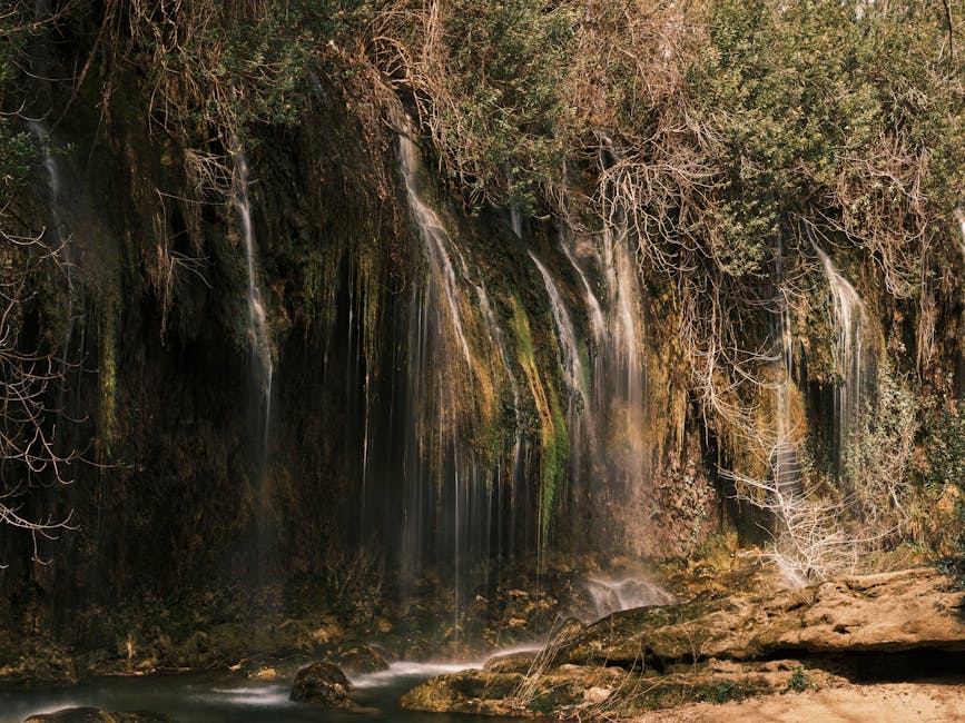 Waterfall flowing over a lush green cliffside in a natural setting