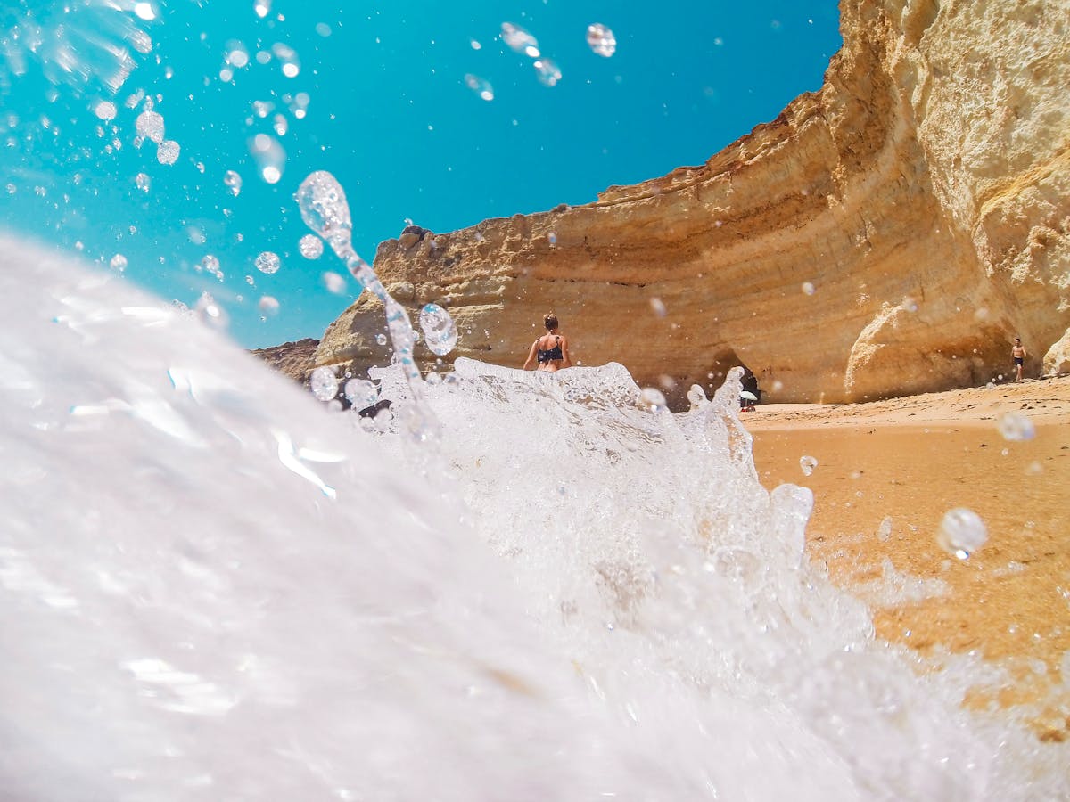 Waves crashing against golden limestone cliffs at a beach in Lagos in the Algarve