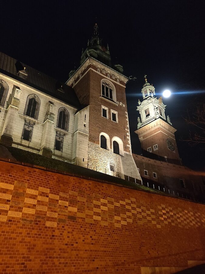 Wawel Cathedral tower lit at night above the Vistula