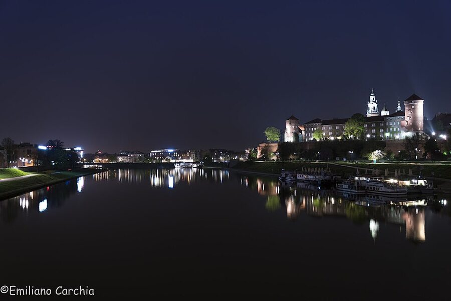 Wawel Castle floodlit walls seen from the river path at night