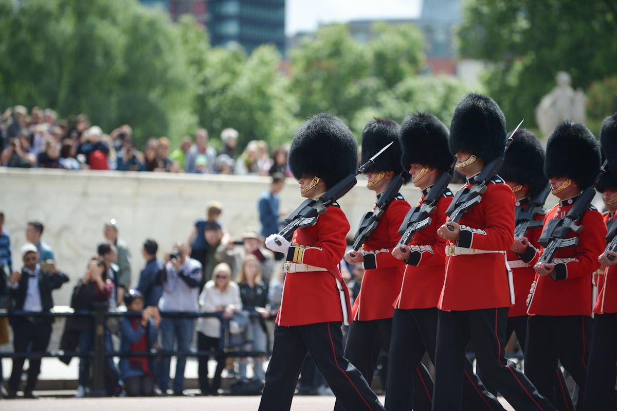 Royal guards in red ceremonial uniforms marching with rifles