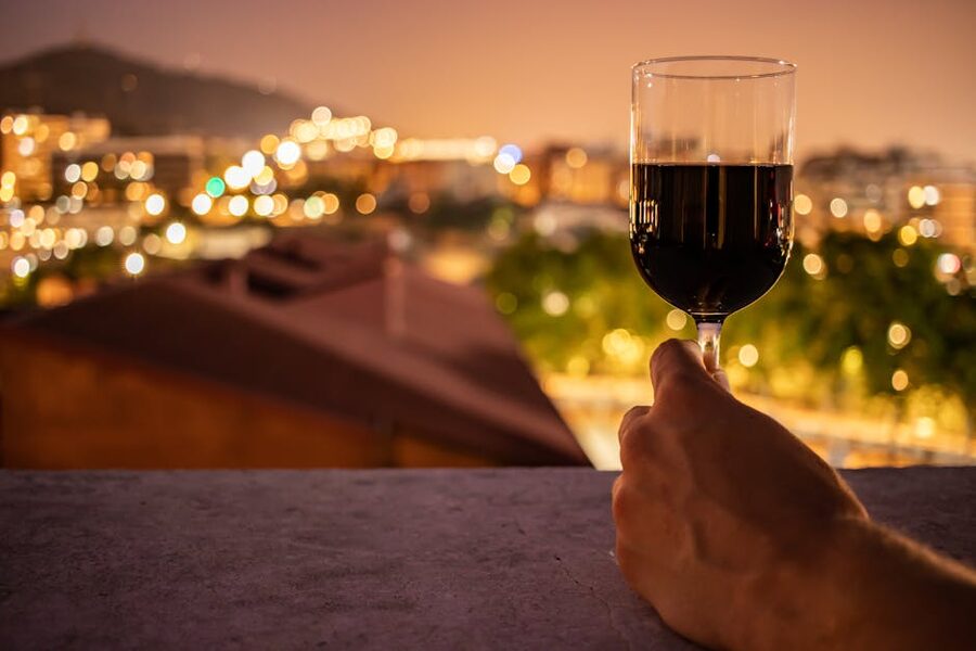 Hand holding a wine glass with night city lights bokeh