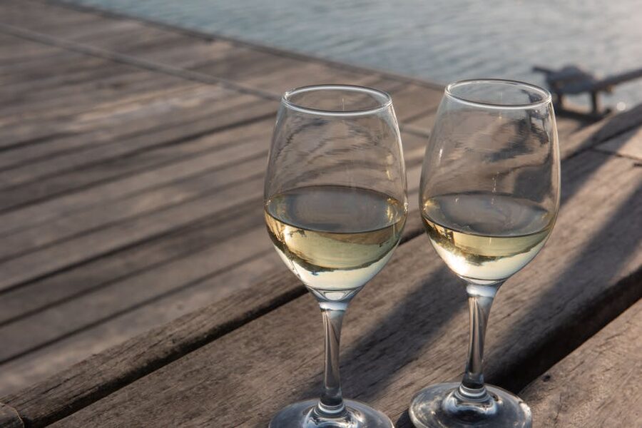 Wine glasses on a wooden deck by the water in the evening