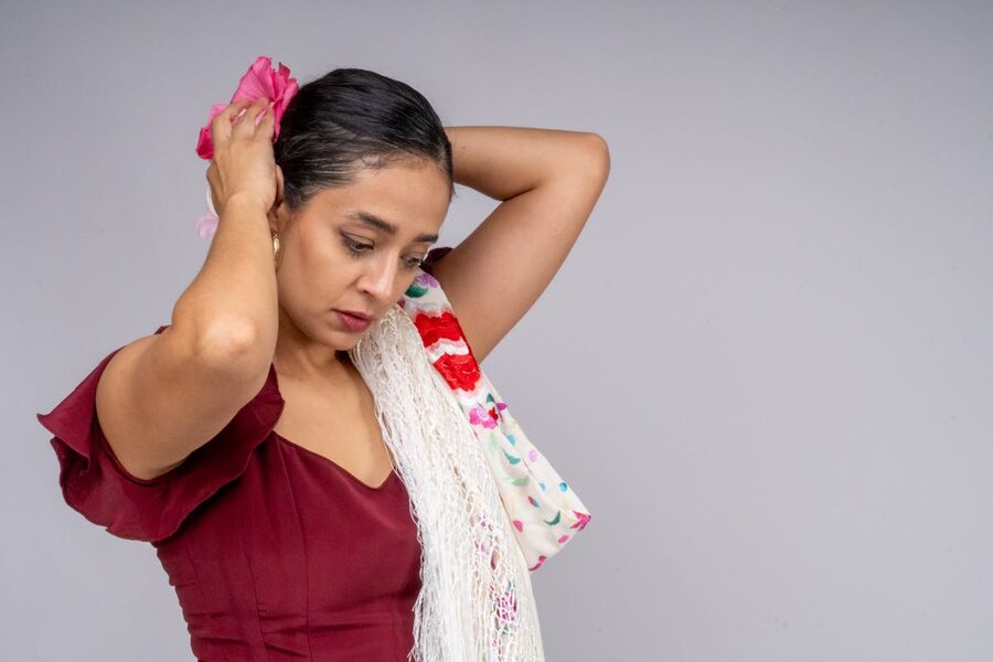 Young woman in red flamenco attire with a floral hair accessory preparing for dance