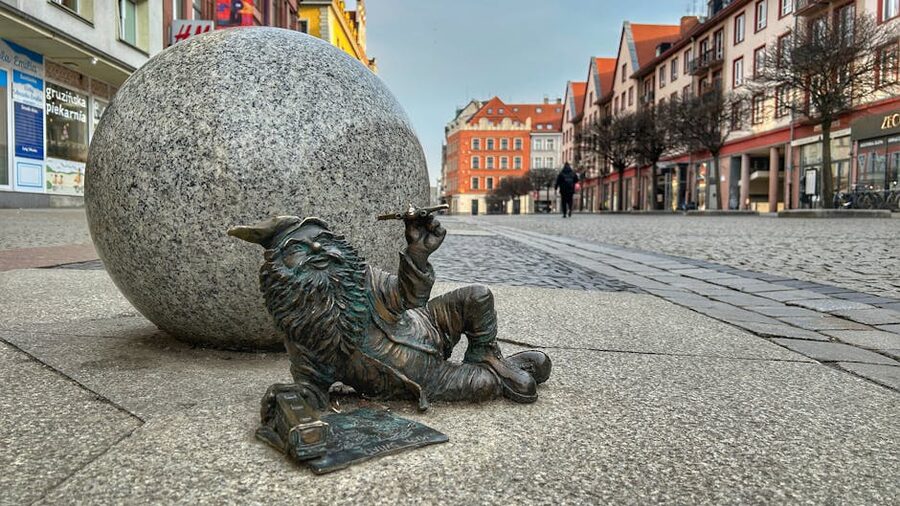 Wroclaw dwarf statue on cobblestone street with colourful buildings