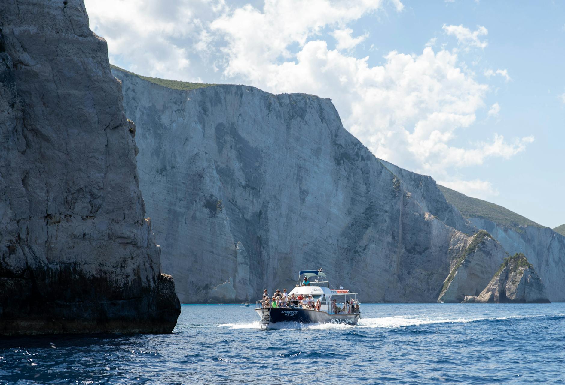 White motor yacht anchored near steep rocky cliffs on the Mediterranean coast
