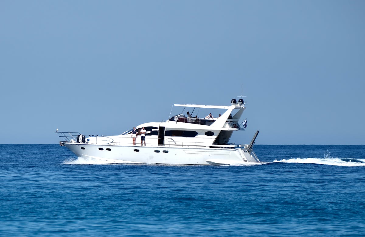 A white yacht cruising through blue water near the coast of Parga in Greece