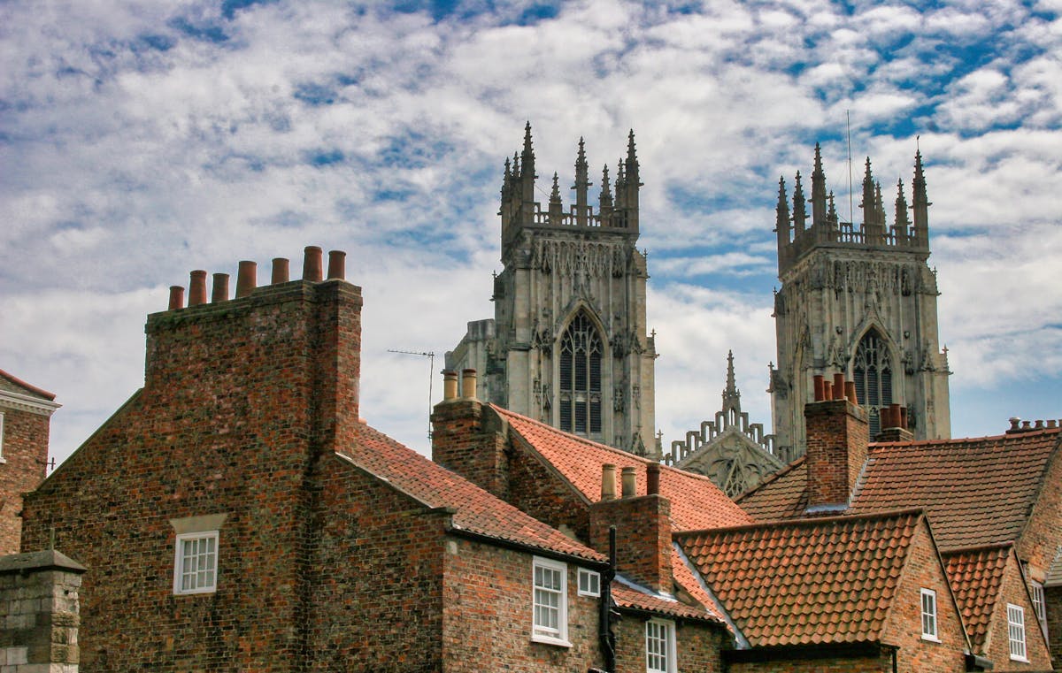 York Minster cathedral rising above surrounding brick buildings against a bright blue sky