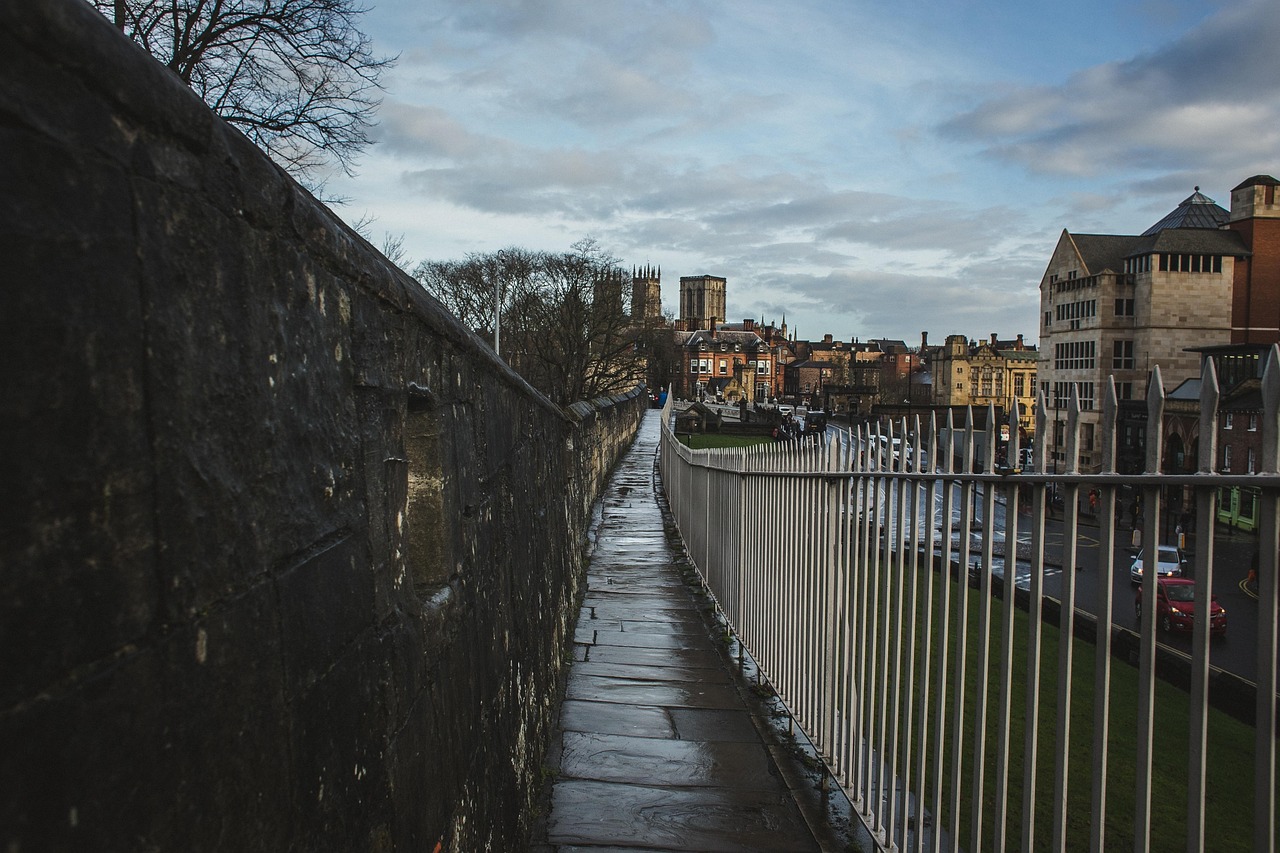 Elevated walkway atop Yorks ancient city walls with stone walls and metal railings