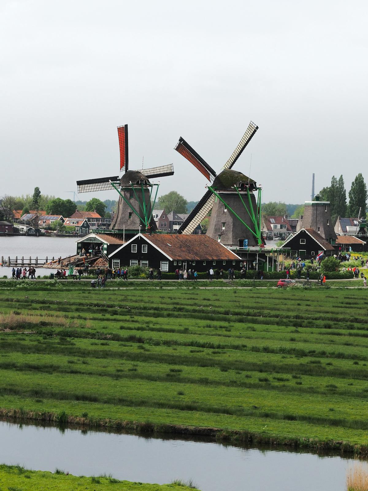 Windmills along the river at Zaanse Schans with green fields