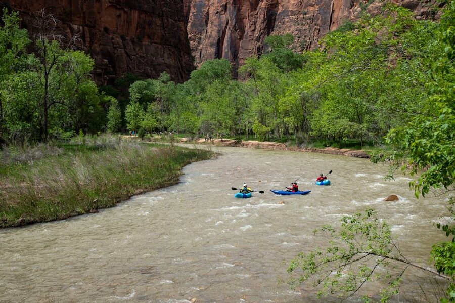 Three kayakers in canyon river
