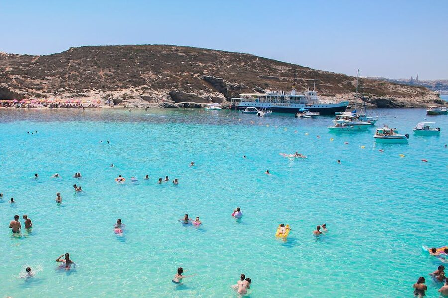 Swimmers and moored day boats at the Blue Lagoon Comino on a sunny summer day