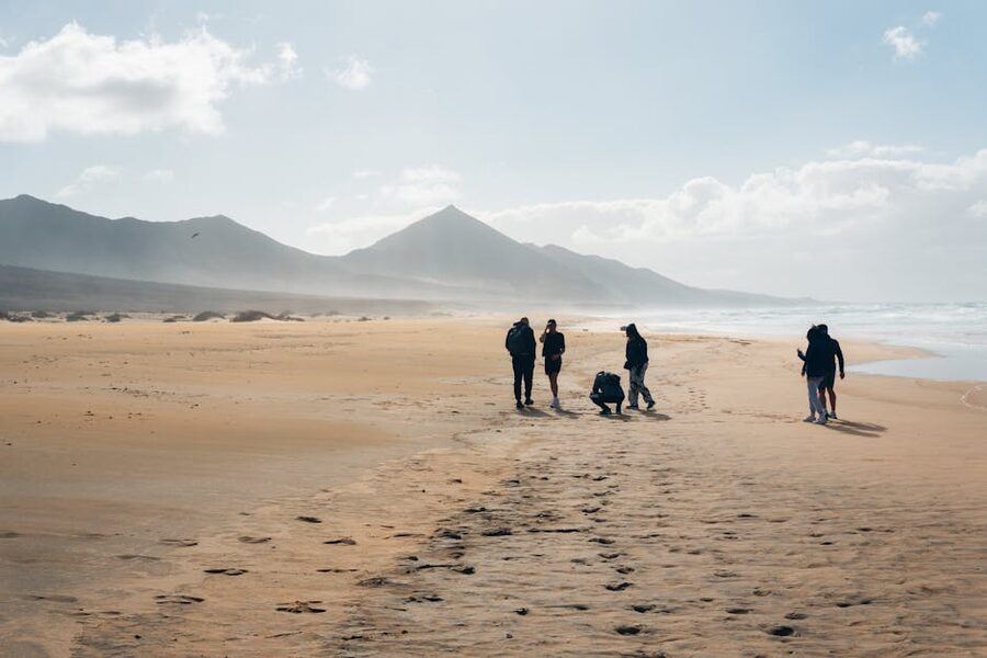 Walkers on Canary Islands beach with mountain backdrop