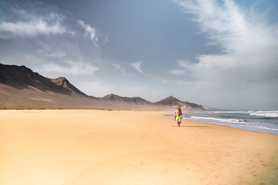 Walkers on a Fuerteventura beach with mountain backdrop