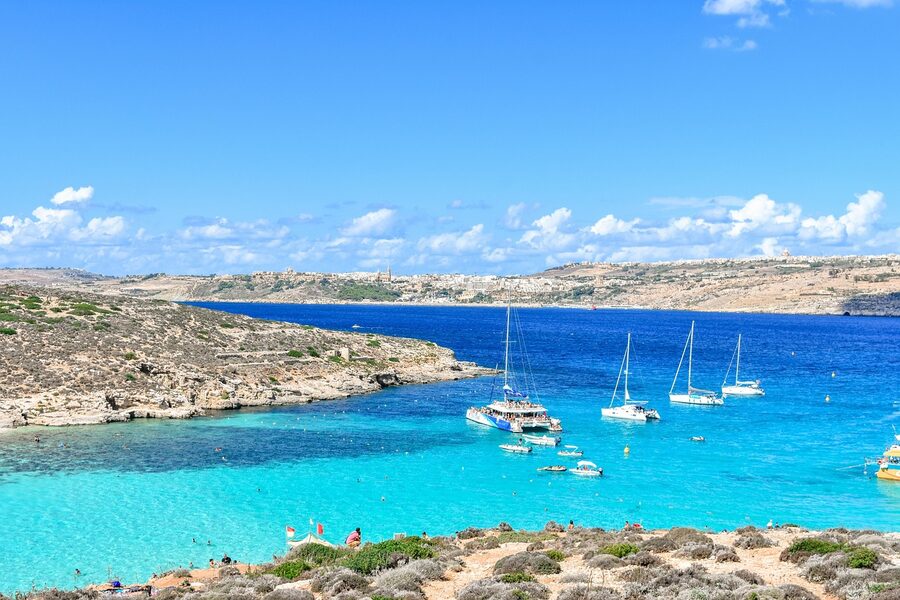 The Blue Lagoon at Comino seen from the cliffs above with Gozo in the distance