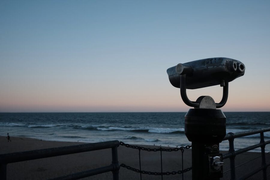Binoculars on a pier overlooking the sea at sunset