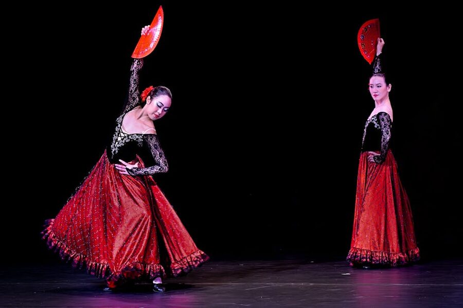 Flamenco dancers performing with red fans at an evening show