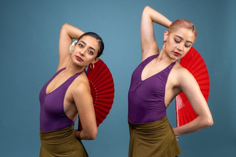 Two flamenco dancers performing with red fans