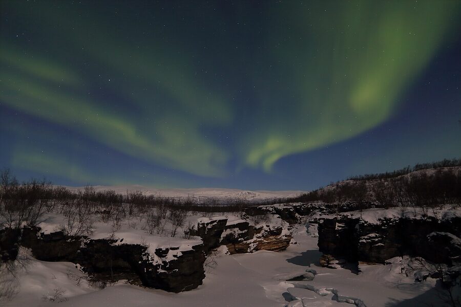 Northern lights ribbon over the frozen Abiskojokk river