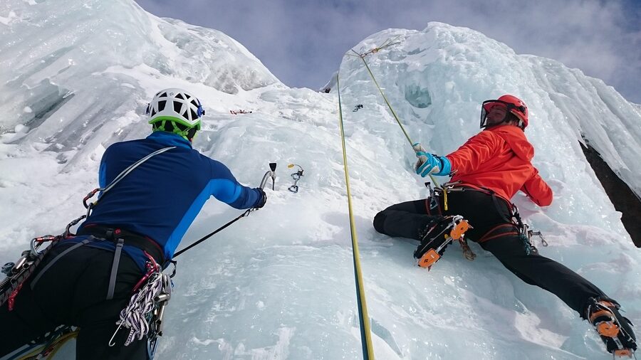 Climbers on a vertical icefall route, ropes hanging