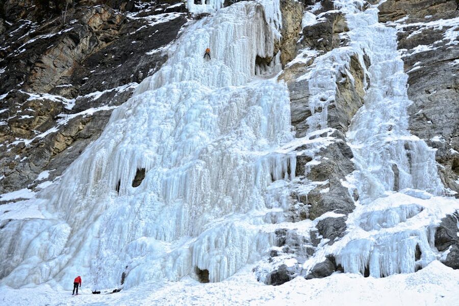 Two climbers working a tall frozen waterfall route