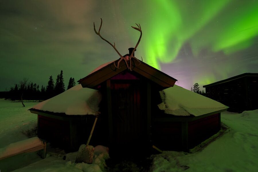 Aurora over a cabin in the snow near Kiruna