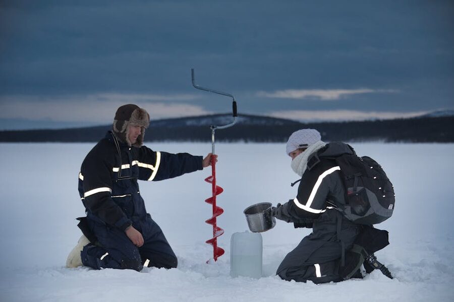 Two people on a frozen lake in Kiruna in winter using ice gear