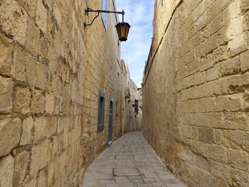 Narrow stone alley in historic Mdina, Malta, lined with limestone walls