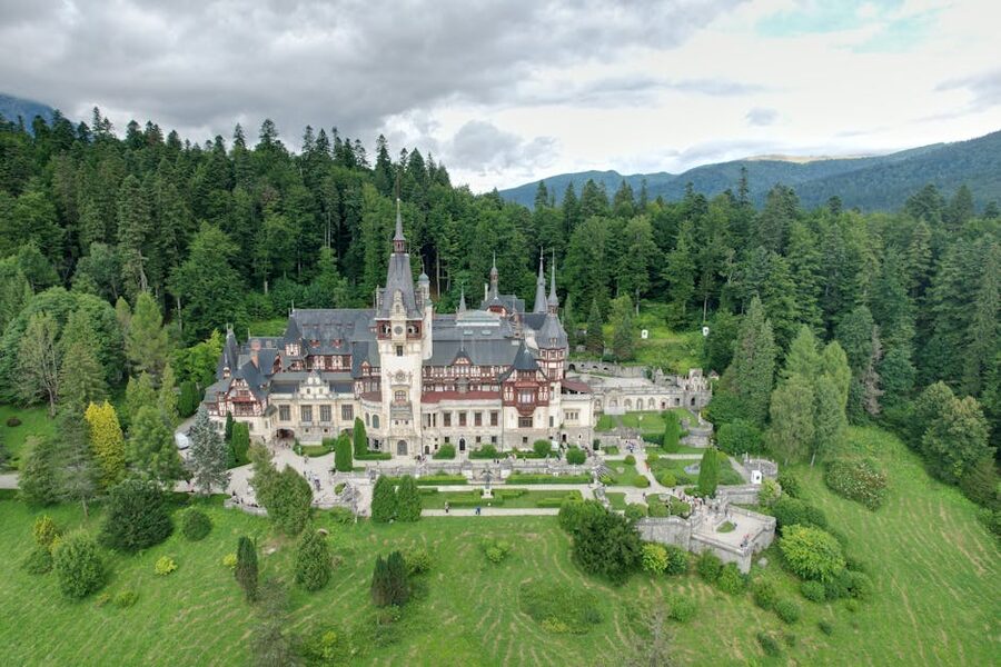 Aerial drone view of Peles Castle surrounded by Carpathian forest