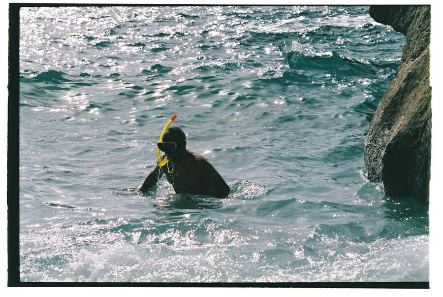 Snorkeler entering blue Mediterranean water from a rocky shore