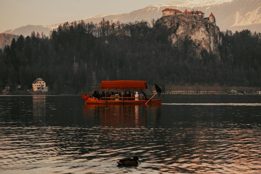 A pletna boat carrying passengers across Lake Bled toward Bled Island