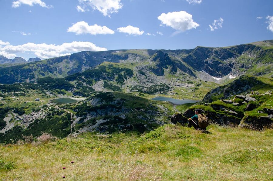 Lone hiker on a Rila Lakes valley path with lake below