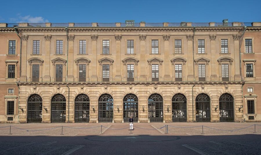 Royal Palace Stockholm under blue sky with single guard at entrance