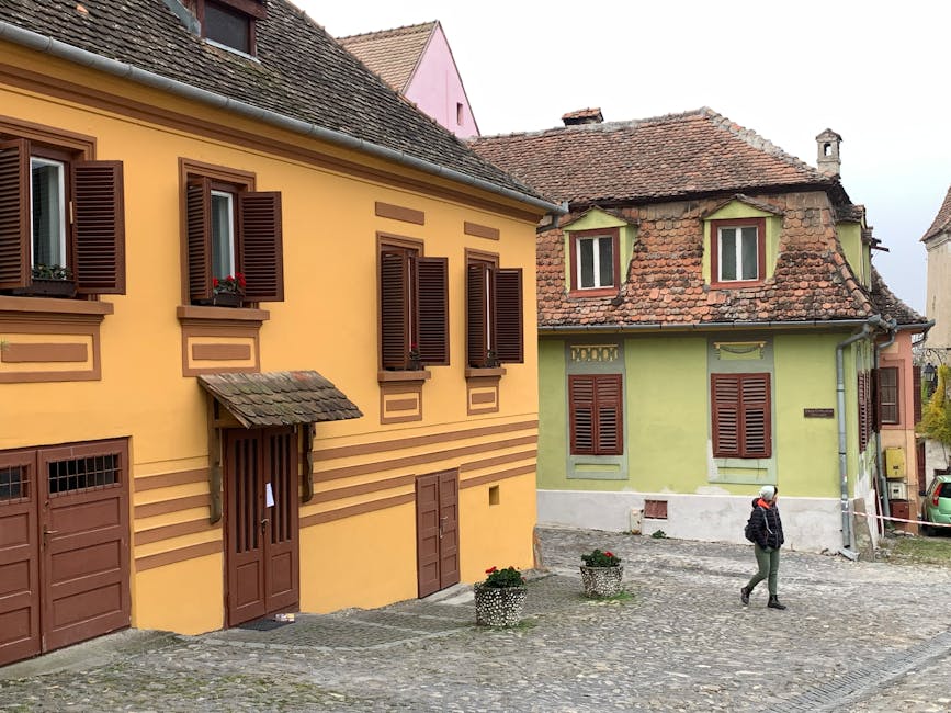 Cobblestone street in Sighisoara with colourful historic buildings and a lone pedestrian