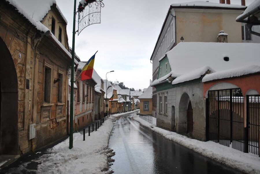 Snowy Sighisoara street with Romanian flag