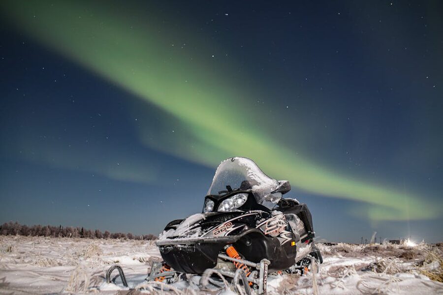 Snowmobile parked under the aurora at night