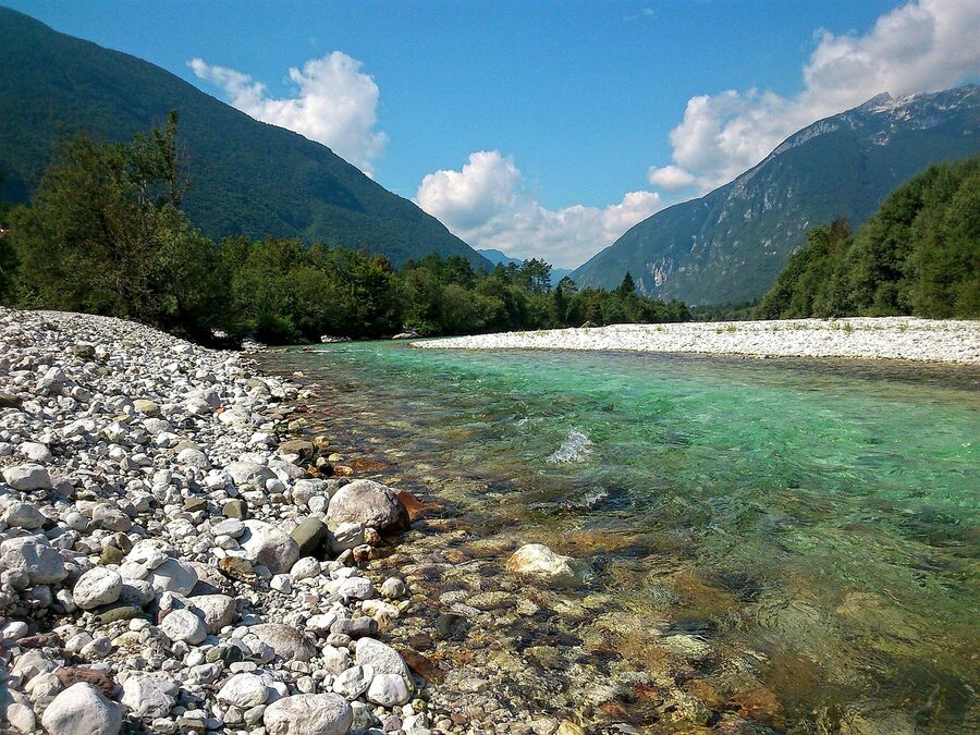 Soca River with white pebble beach and turquoise water in summer