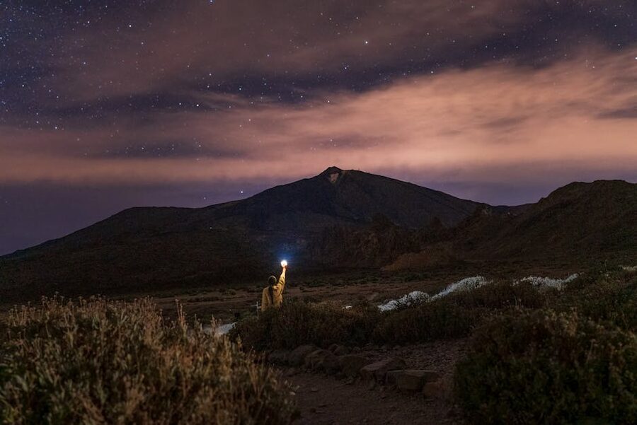 A woman holding a flashlight under a starry sky in Santiago del Teide, Tenerife
